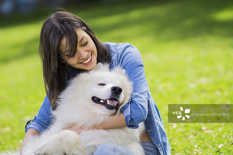 快乐的年轻女子拥抱她的狗并微笑图片素材