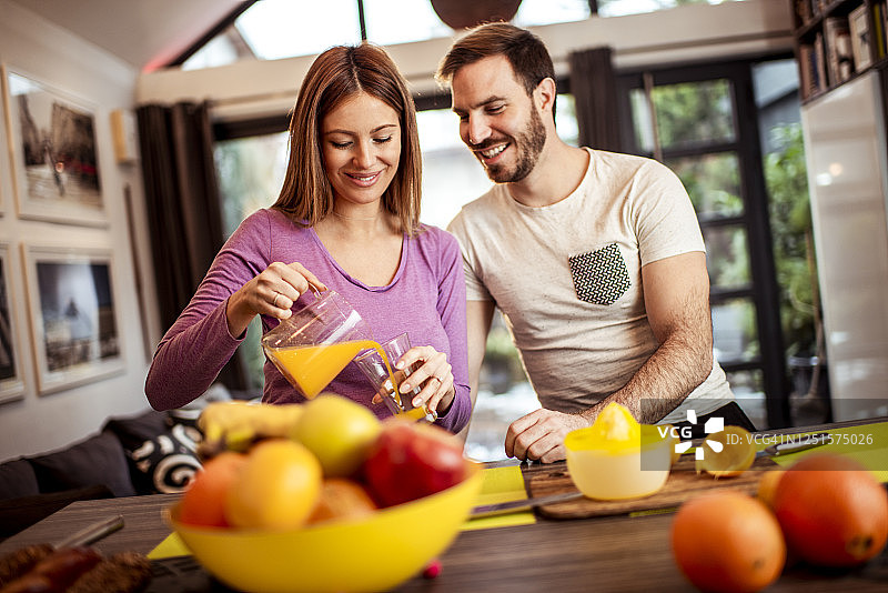 年轻夫妇在家中餐厅一起榨橙汁图片素材