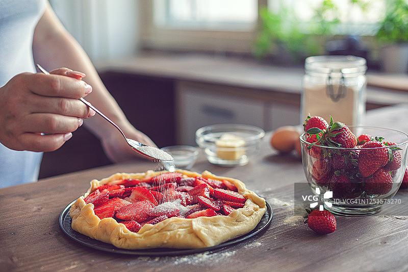 年轻女人准备草莓馅饼或开放式草莓派图片素材