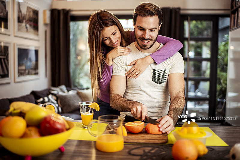 男子准备健康膳食，他的伴侣从背后抱着他图片素材