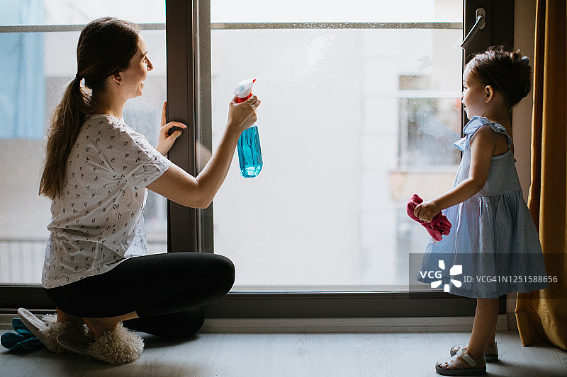 母亲和可爱的女儿一起清洁窗户图片素材