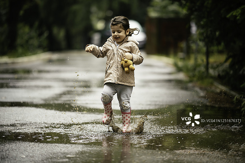 快乐的小女孩在雨中跳跃的库存照片图片素材