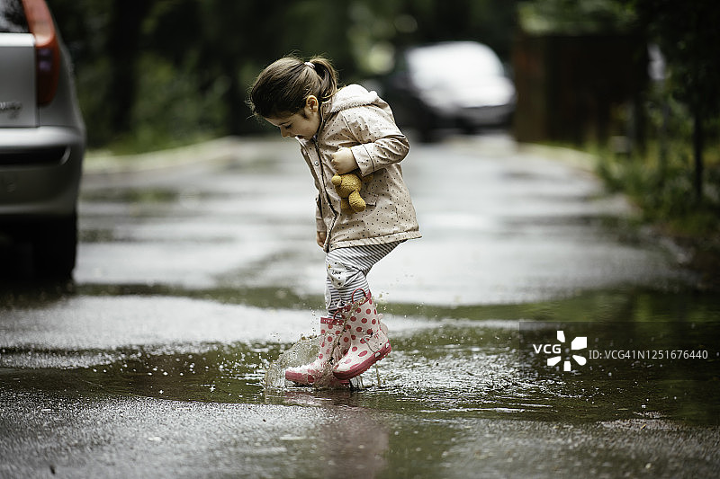 快乐的小女孩在雨中跳跃的库存照片图片素材