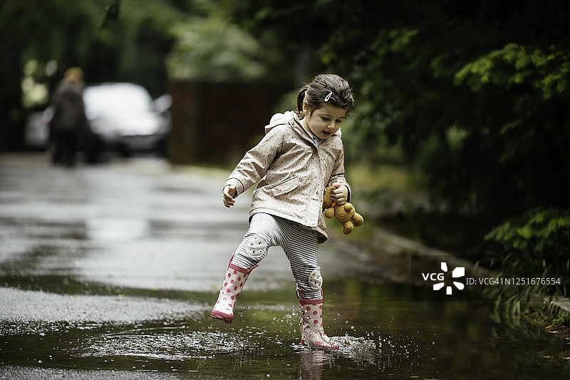 快乐的小女孩在雨中跳跃的库存照片图片素材