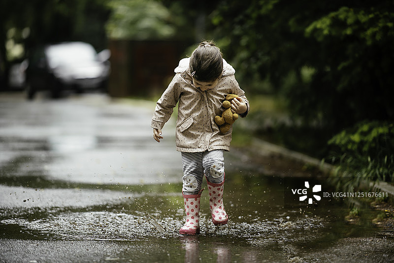 快乐的小女孩在雨中跳跃的库存照片图片素材