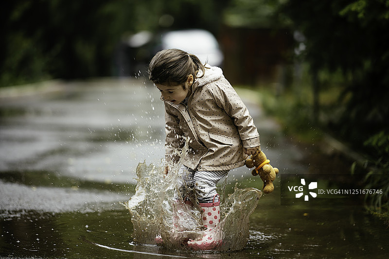 快乐的小女孩在雨中跳跃的库存照片图片素材
