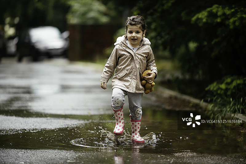 快乐的小女孩在雨中跳跃的库存照片图片素材
