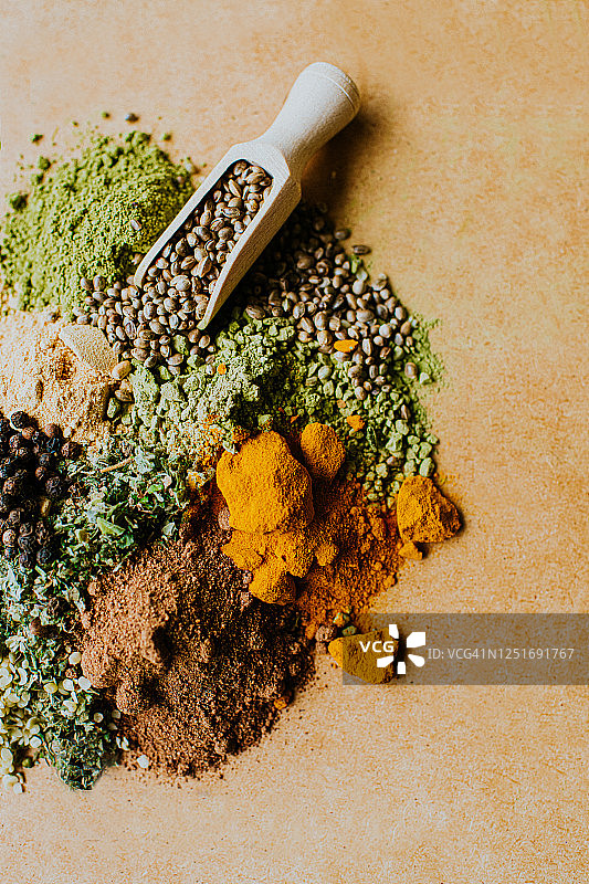 木质表面上的香草、香料和调味料堆，带勺子图片素材