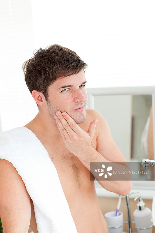 年轻男人在浴室里使用须后水图片素材