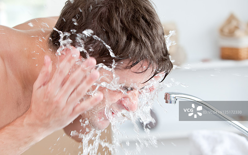 男人剃须后在浴室往脸上喷水图片素材