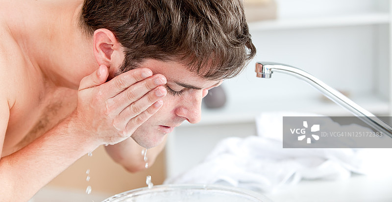年轻男人在浴室刮胡子后往脸上喷水图片素材