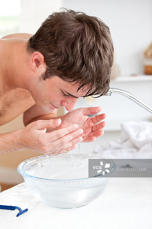 男人剃须后在浴室往脸上喷水图片素材