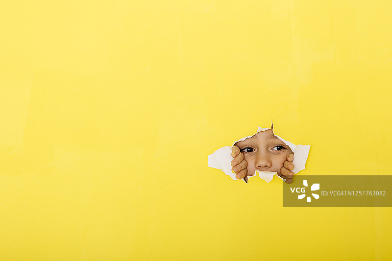 好奇的男孩撕开黄纸窥视特写镜头图片素材