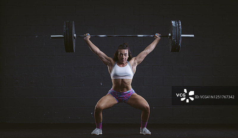 年轻女人在健身房练习杠铃深蹲图片素材