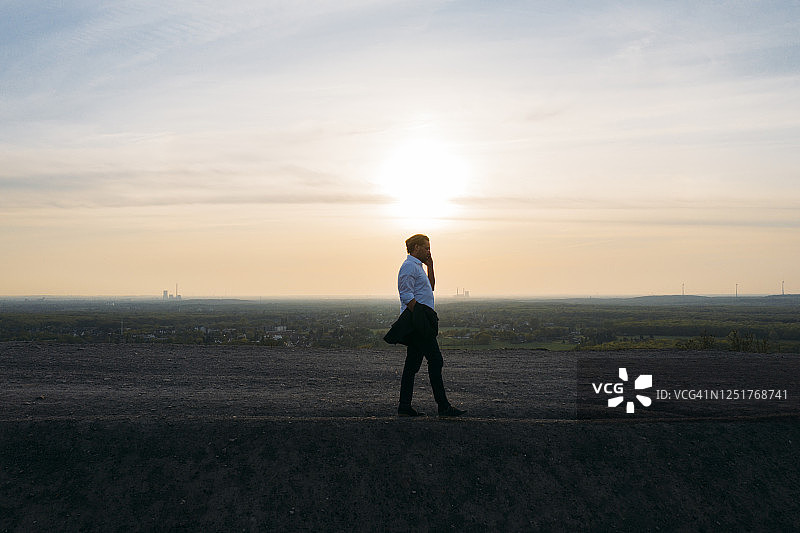 日落时分在山坡上对着天空行走的商人图片素材