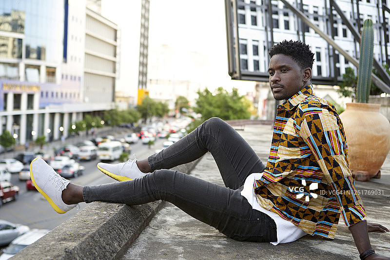 莫桑比克马普托：身穿花衬衫的年轻男人坐在屋顶露台上图片素材