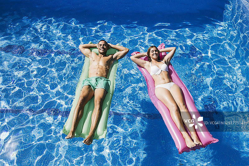 年轻情侣在游泳池里放松身心图片素材