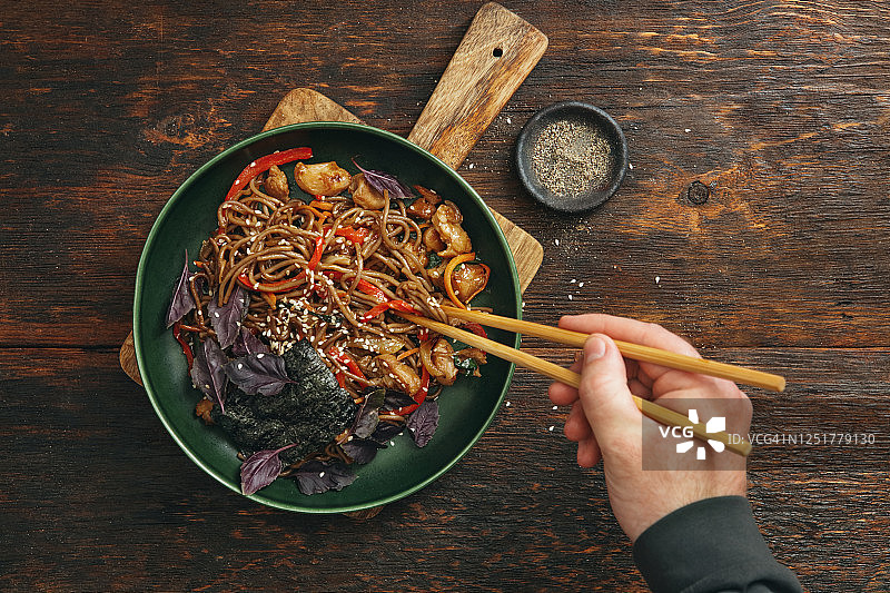 成年男子享用日式炒面，配鸡肉和蔬菜图片素材