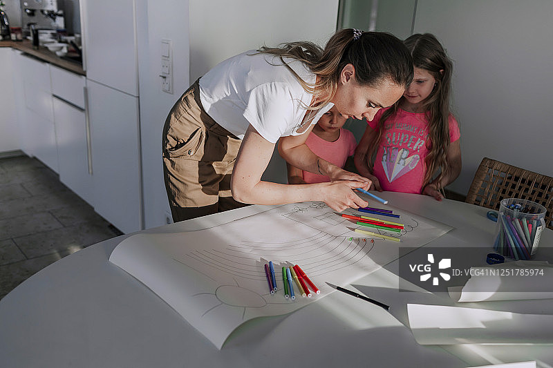 母亲在家帮助女儿们在纸上绘画图片素材