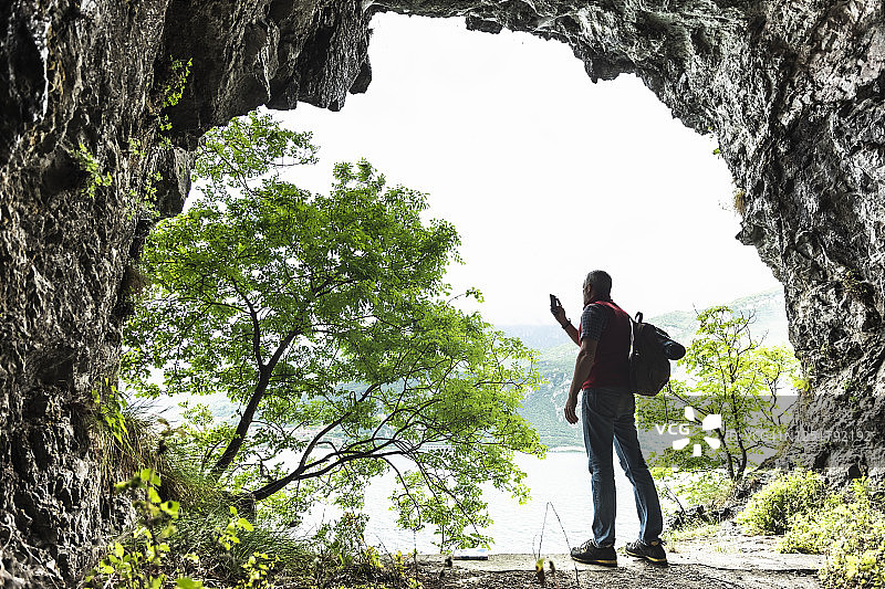 从洞穴入口处拍摄科莫湖的成熟男探险家图片素材