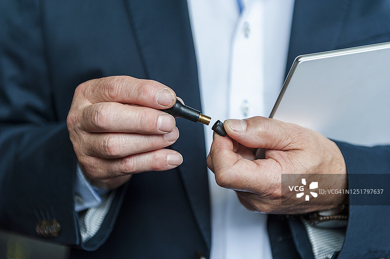 拿着气门和数字平板电脑的年长的男企业家图片素材