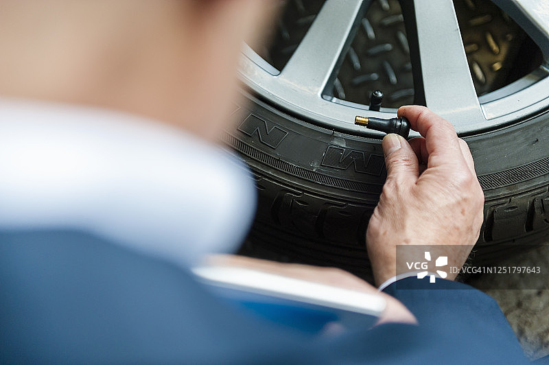 年长的商人在商店里拿着轮胎的气门图片素材