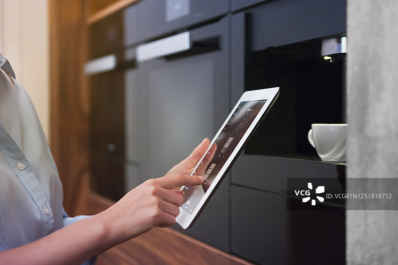 中年女人在现代厨房中使用平板电脑图片素材