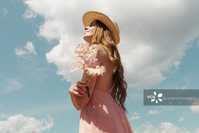 阳光下享受鲜花的红发女子肖像图片素材