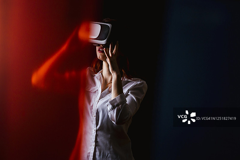 年轻女人使用VR眼镜，黑色背景图片素材
