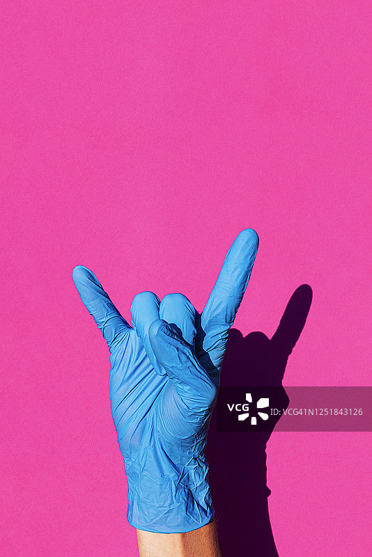 戴乳胶手套的女性手部做出摇滚手势图片素材