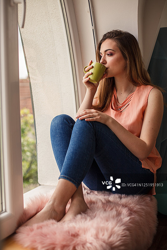 年轻女人在窗边喝茶图片素材