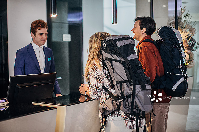 情侣在酒店前台与男接待员交谈图片素材