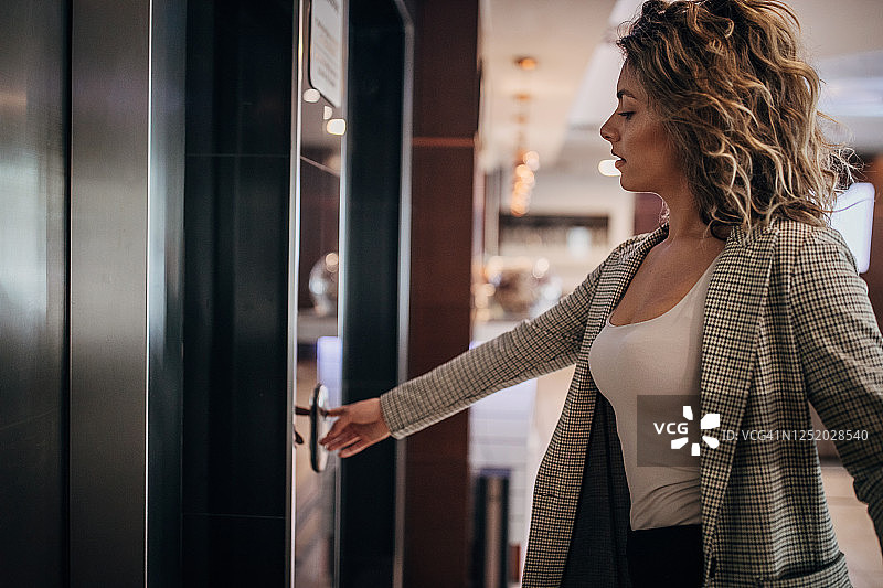 年轻女商人在酒店大堂呼叫电梯图片素材