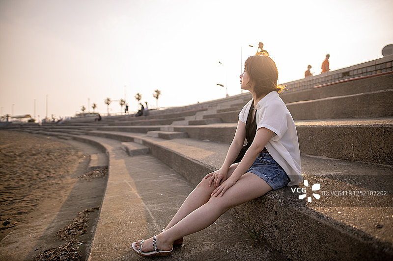年轻女子独自在日落时分的海滩放松身心图片素材