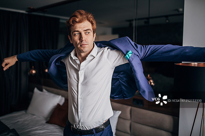 身穿蓝色西装的现代男人在酒店房间里图片素材