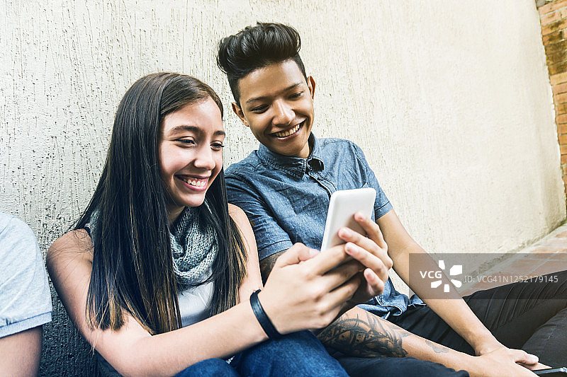 幸福的年轻夫妇在智能手机上看社交媒体聊天图片素材