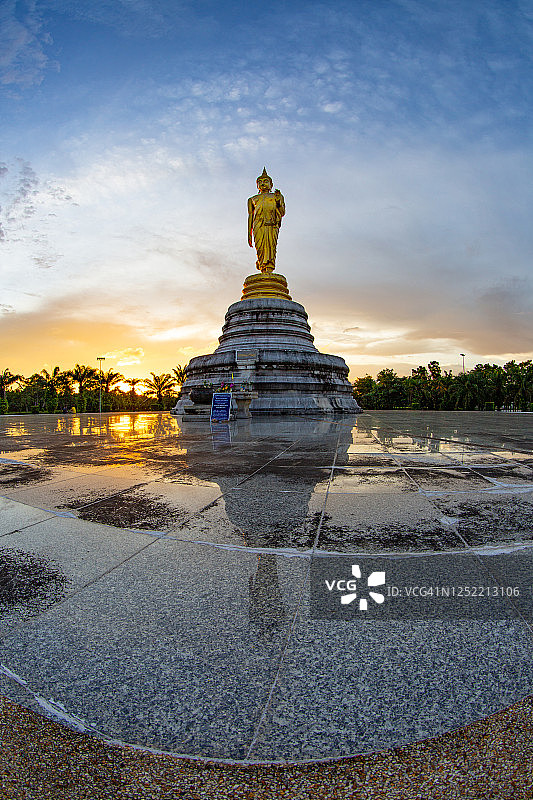 金色佛像在日落时分祝福众生，倒影在旧瓷砖地板上图片素材