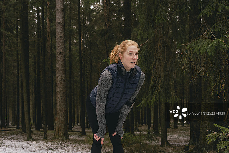 在雪地树林中休息的女跑步者图片素材
