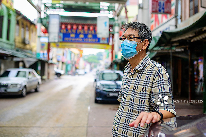 在吉隆坡唐人街戴着防护口罩微笑的亚洲男人图片素材