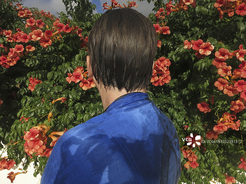 在阳光明媚的花园里，头发湿漉漉的女人站在花丛中图片素材