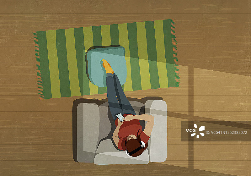 女人戴着耳机用智能手机听音乐，在扶手椅上放松图片素材