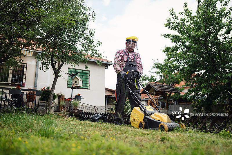 年长的男人用割草机修剪草坪图片素材