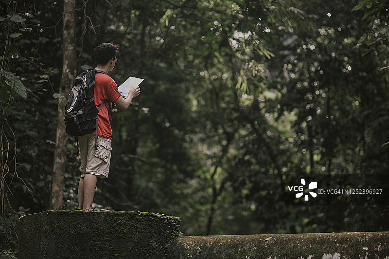 中国年轻男子在丛林雨林的徒步小径上看地图图片素材