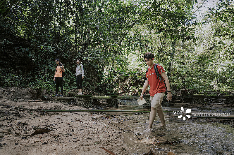 三位亚洲华裔朋友在森林中穿过河上的桥梁丛林徒步旅行图片素材