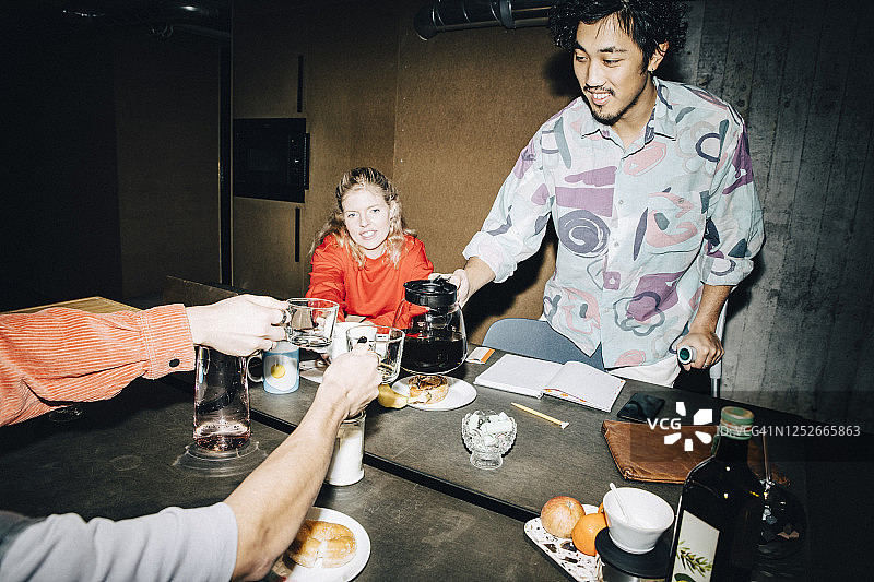 年轻女商人在工作场所与同事喝咖啡的画像图片素材