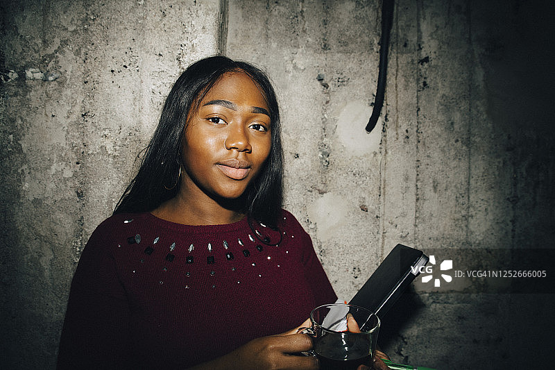 女性创业者在工作场所靠墙站立，手持笔记本电脑图片素材