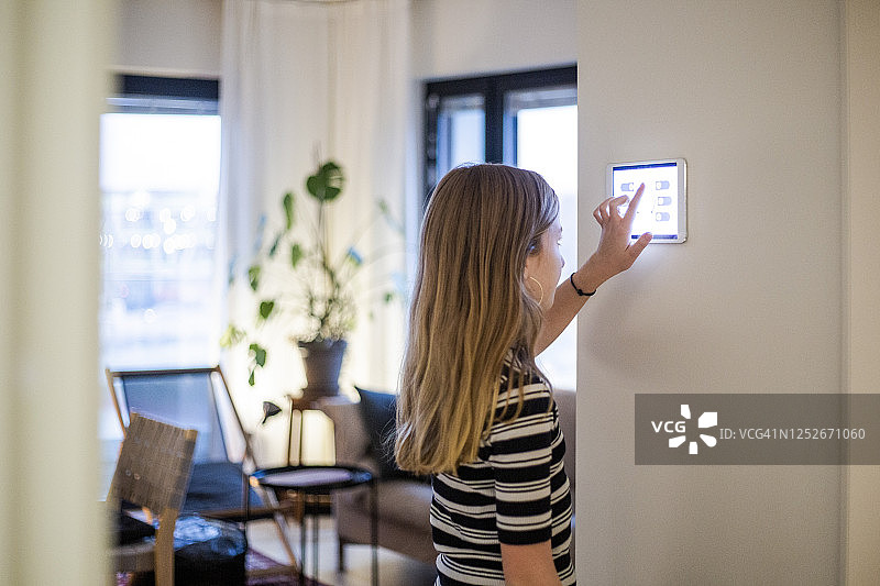 在现代住宅墙上使用平板电脑的女孩图片素材