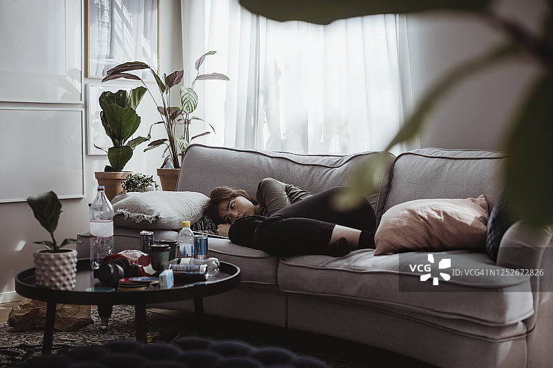 躺在家中沙发上的焦虑年轻女人图片素材