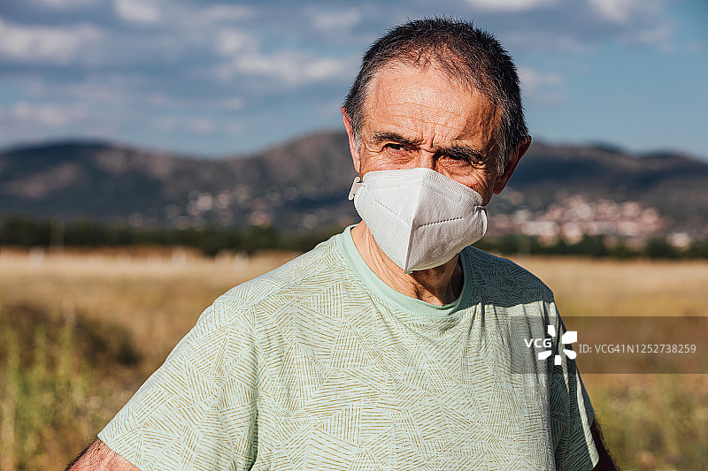 戴口罩在田野中的年长男人肖像图片素材