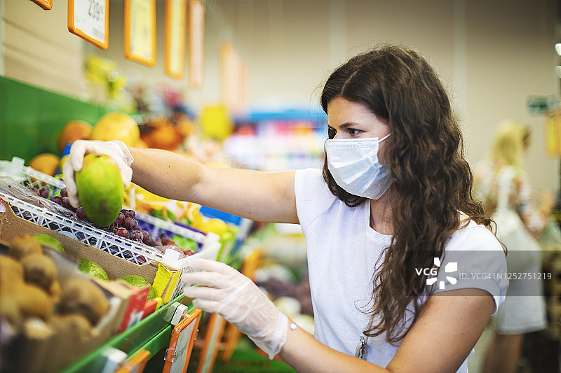 隔离期间戴防护面罩买水果的女人图片素材